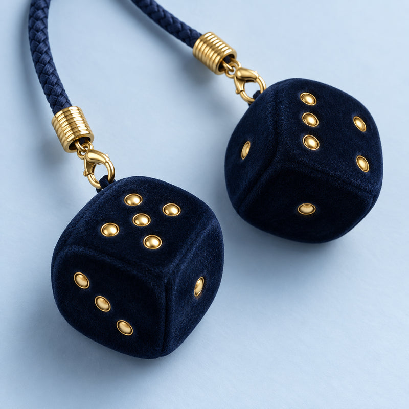 Nahaufnahme der navyblauen Safety Dice mit goldfarbenen Punkten, Karabinern und geflochtenem Band